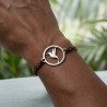 Bracelet colibri en titane poli porté au poignet, cordon tissé noir, vert et rouge