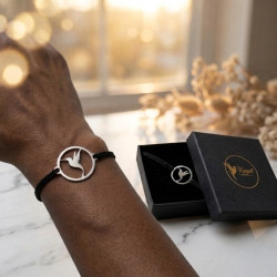 Poignet portant le bracelet Madinina Spirit à cordon noir, à côté du coffret ouvert