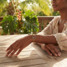 Femme portant le bracelet Madinina Spirit, main posée sur une table, végétation tropicale