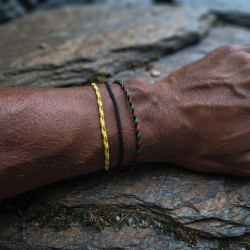 Trois cordons ronds, jaune madras, noir et rouge-noir-vert, portés au poignet
